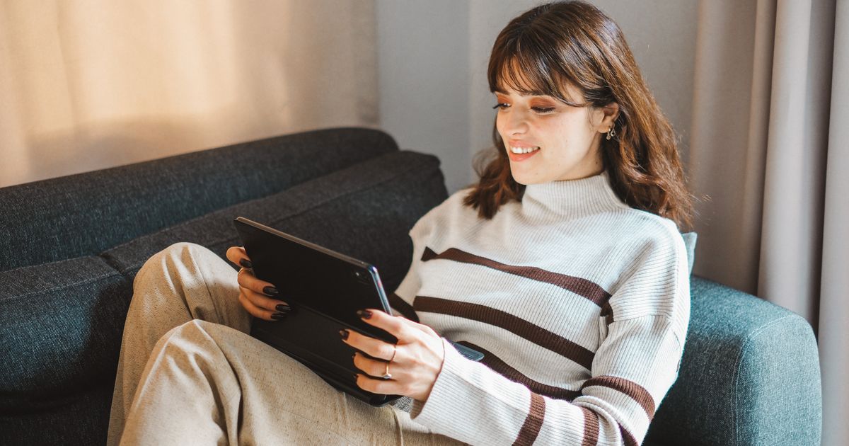 ソファでタブレットを使う女性
